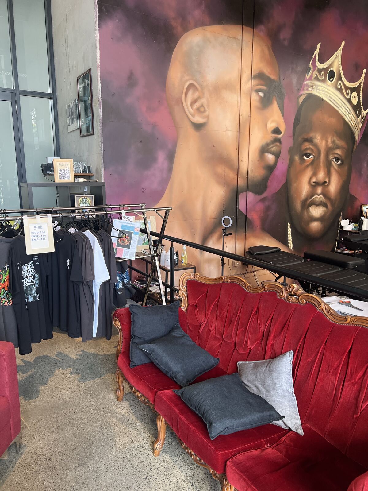 Red velvet lounge and merch rack under the mural