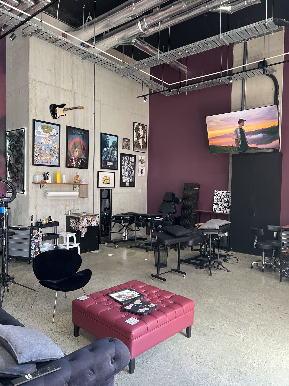 Tattoo stations, framed posters and the burgundy wall